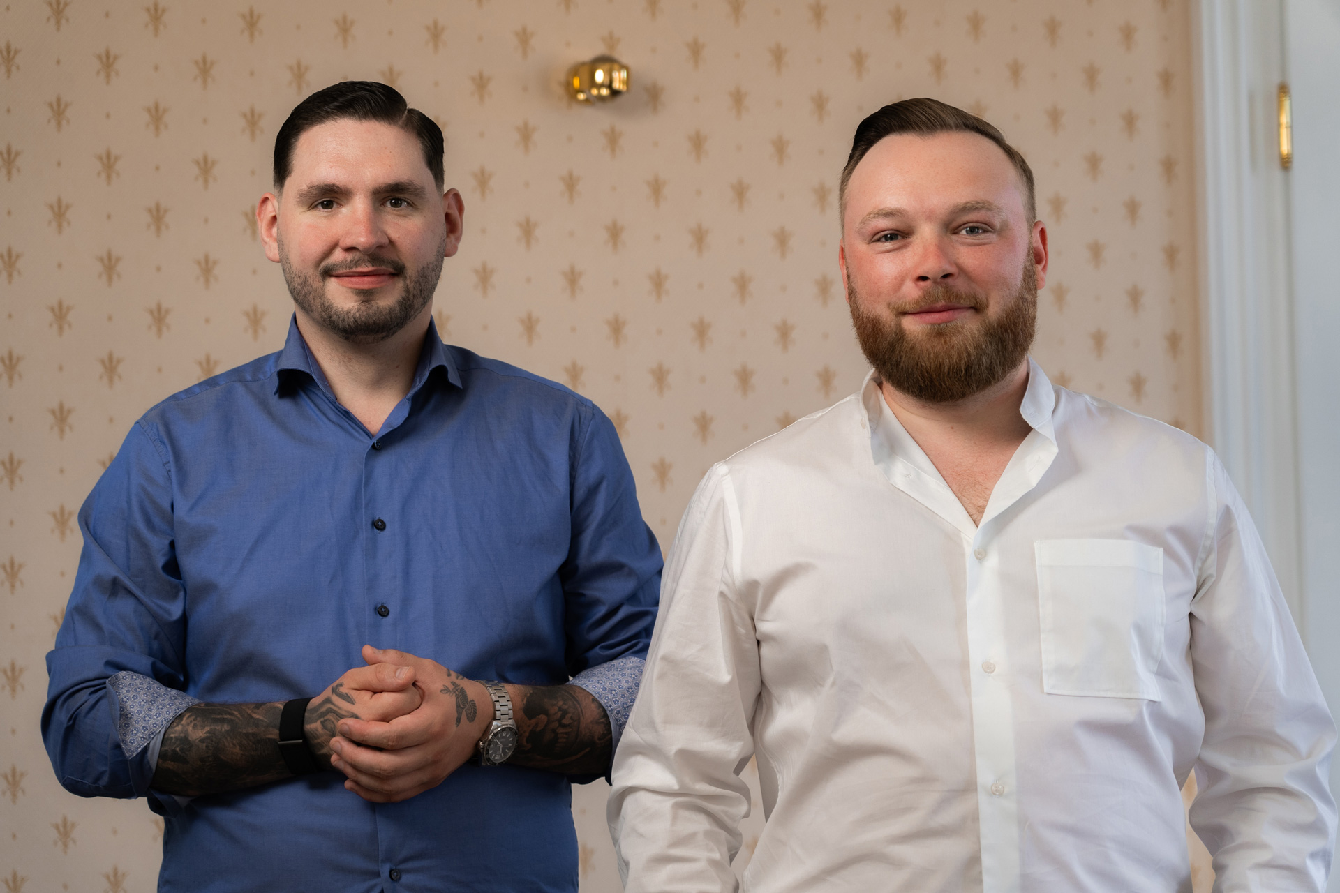 Ein portrait von zwei Jungen Männern. Sie sind schick angezogen und lächeln