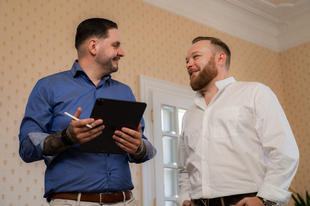 Zwei Männer unterhalten sich gut gelaunt, während einer ein Tablet in der Hand hält.