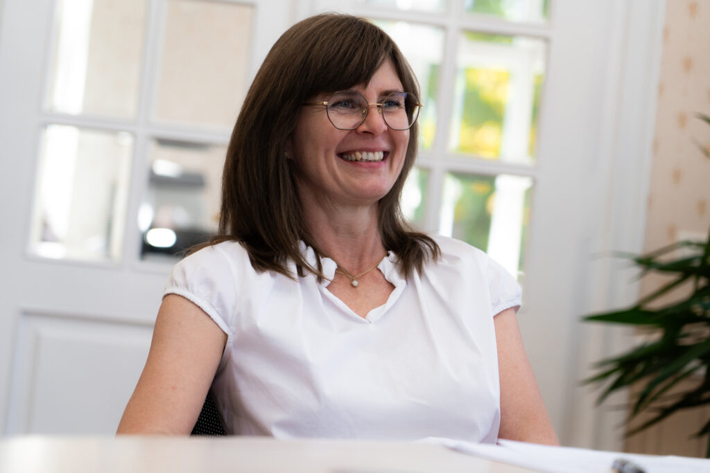 Ein Portrait einer Frau mit Brille die lächelt.